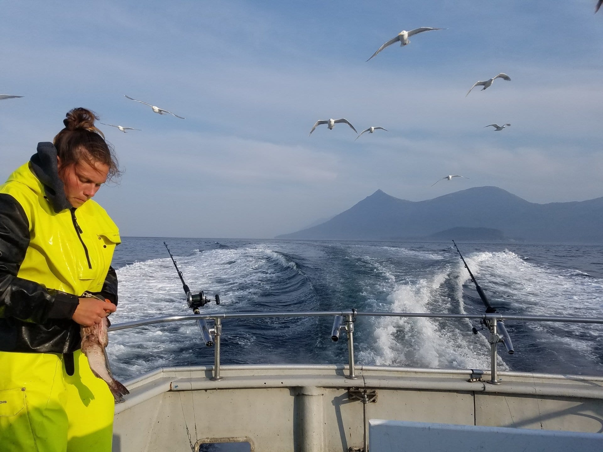 person on boat removing hook from a fish