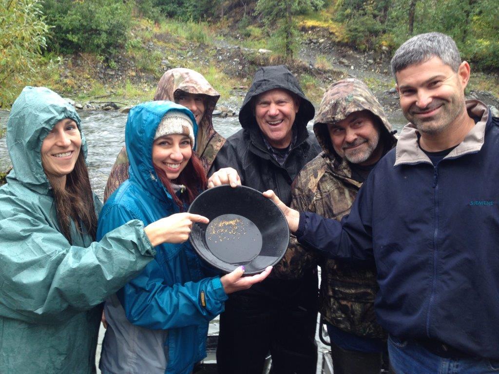 people showing off gold while panning for gold