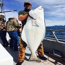 man holding halibut on Alaskan boat