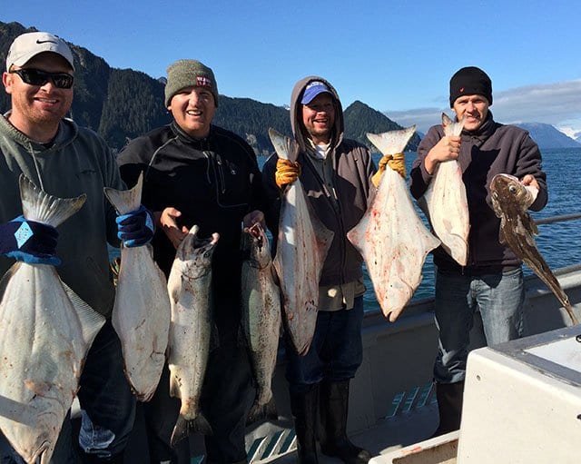people in Alaska holding salmon and halibut