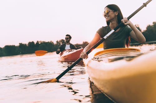 Male and female couple kayaking in calm waters during dawn or dusk hours