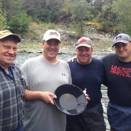 4 guys holding pan with gold