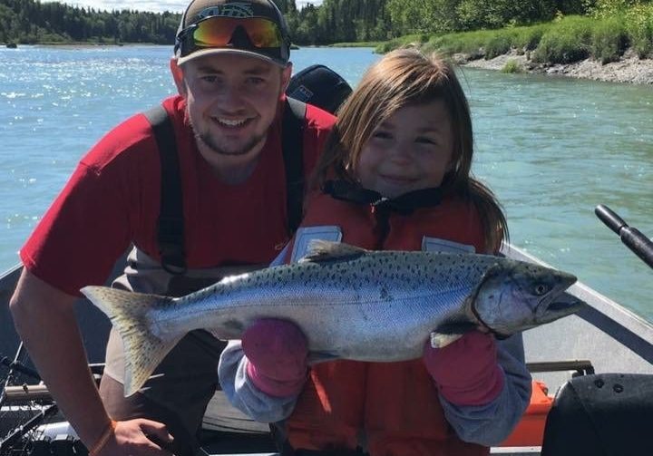 father and daughter holding a fresh caught salmon
