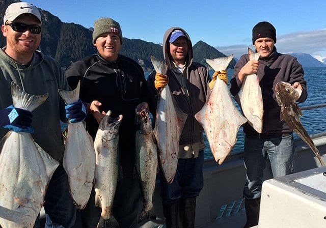 people in Alaska holding salmon and halibut