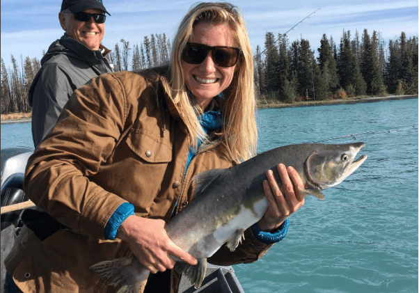 woman holding a salmon like a rocket launcher