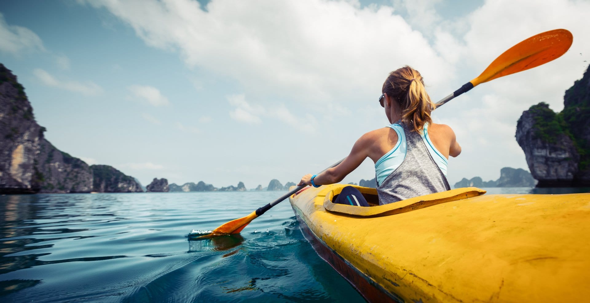 young woman paddling in yellow kayak