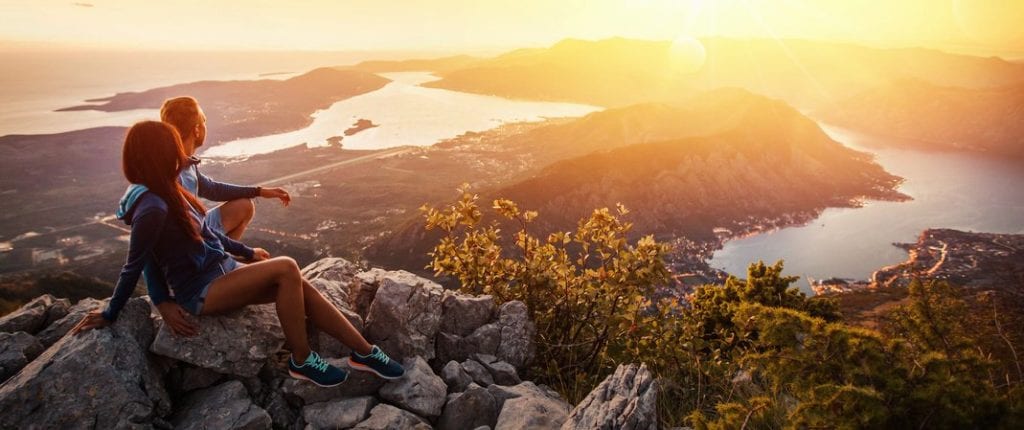 couple sitting on rocks overlooking Alaska