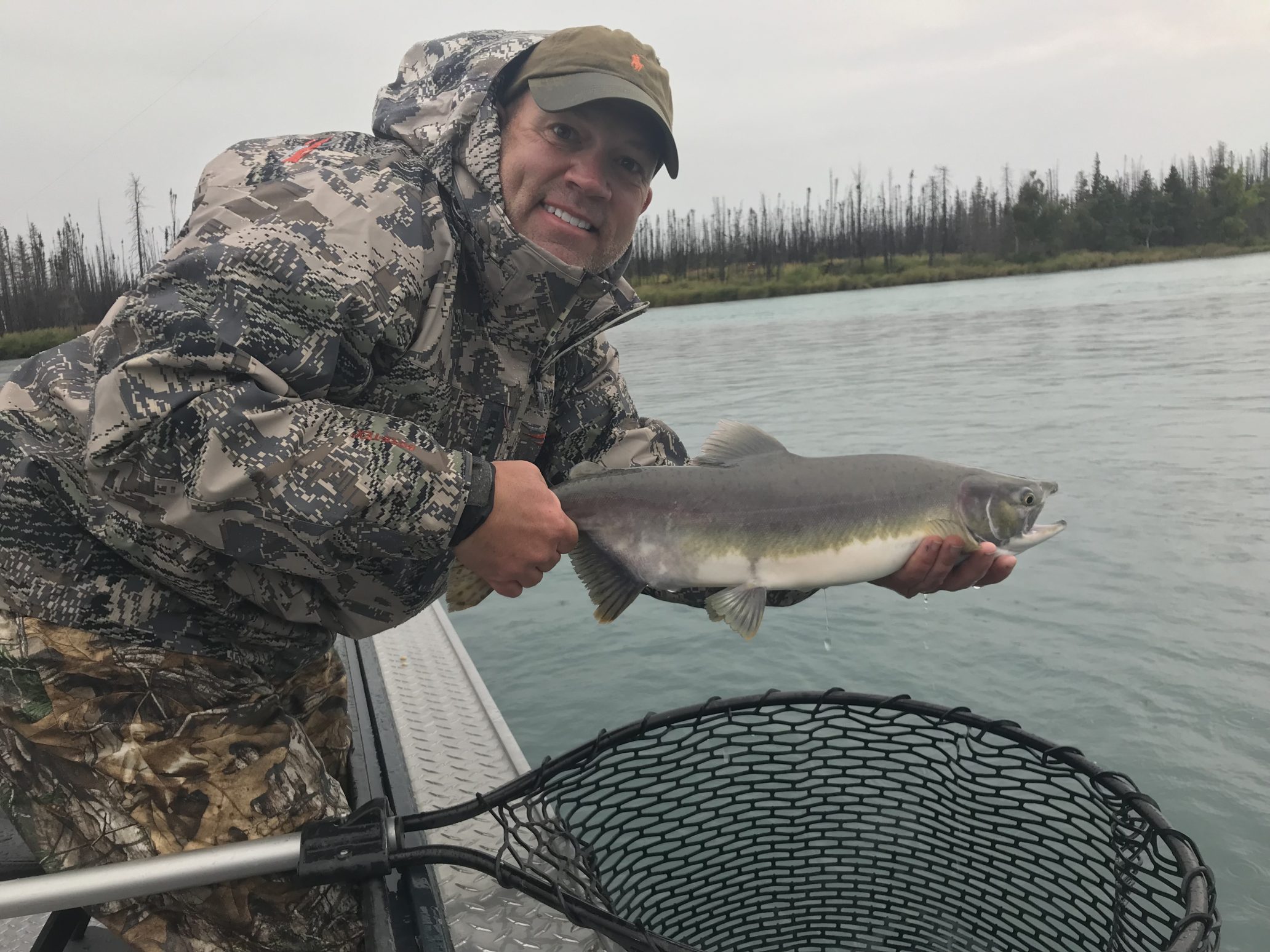 bundled up proud guy holding a fish he caught