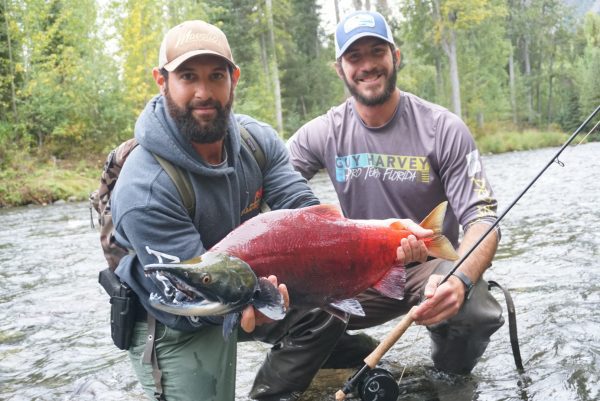 two men showing off a sockeye salmon in alaska
