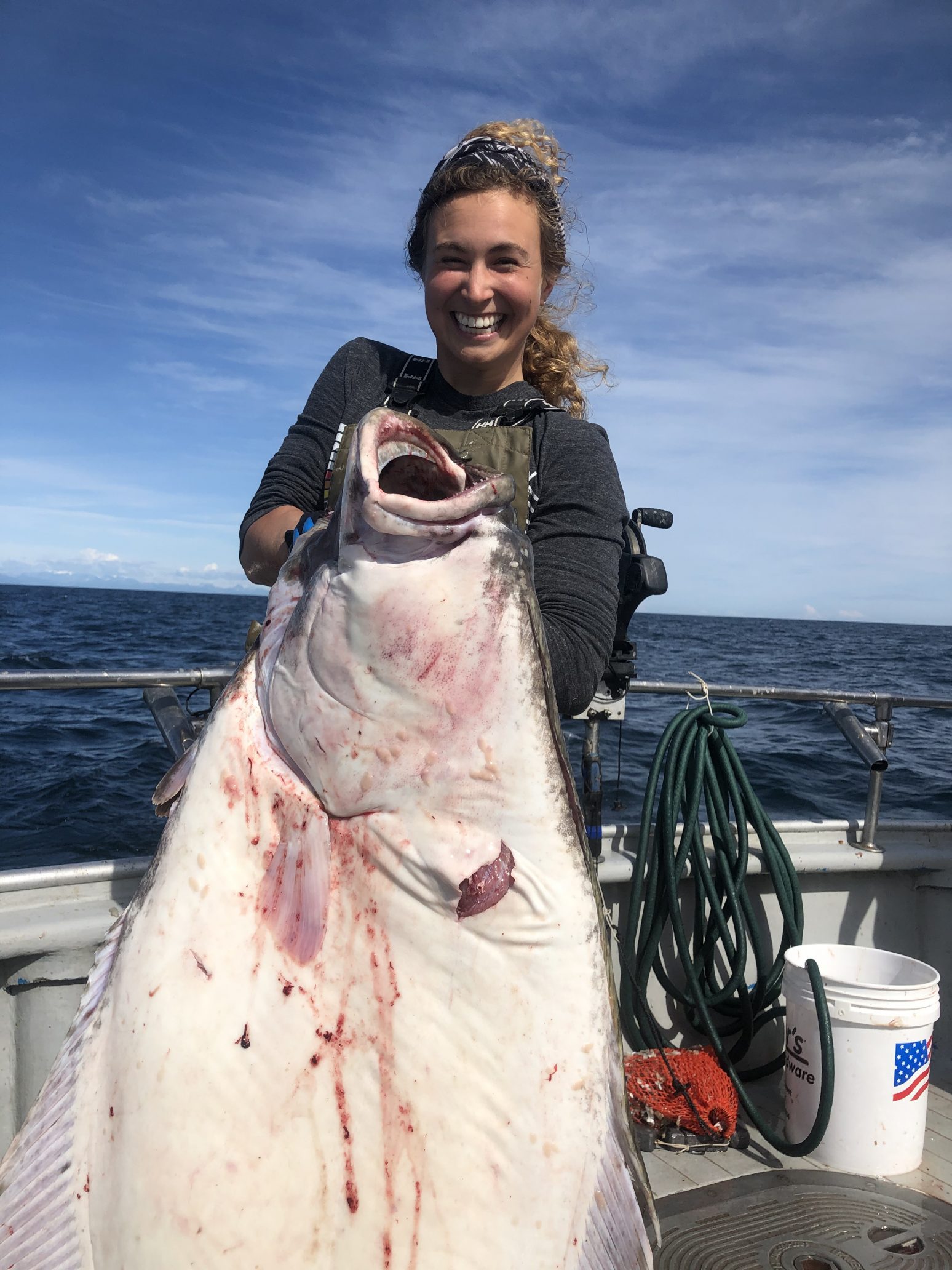 woman holding a halibut that's larger than she is
