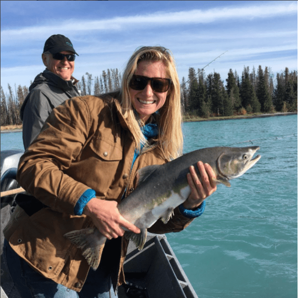 woman holding a salmon like a rocket launcher